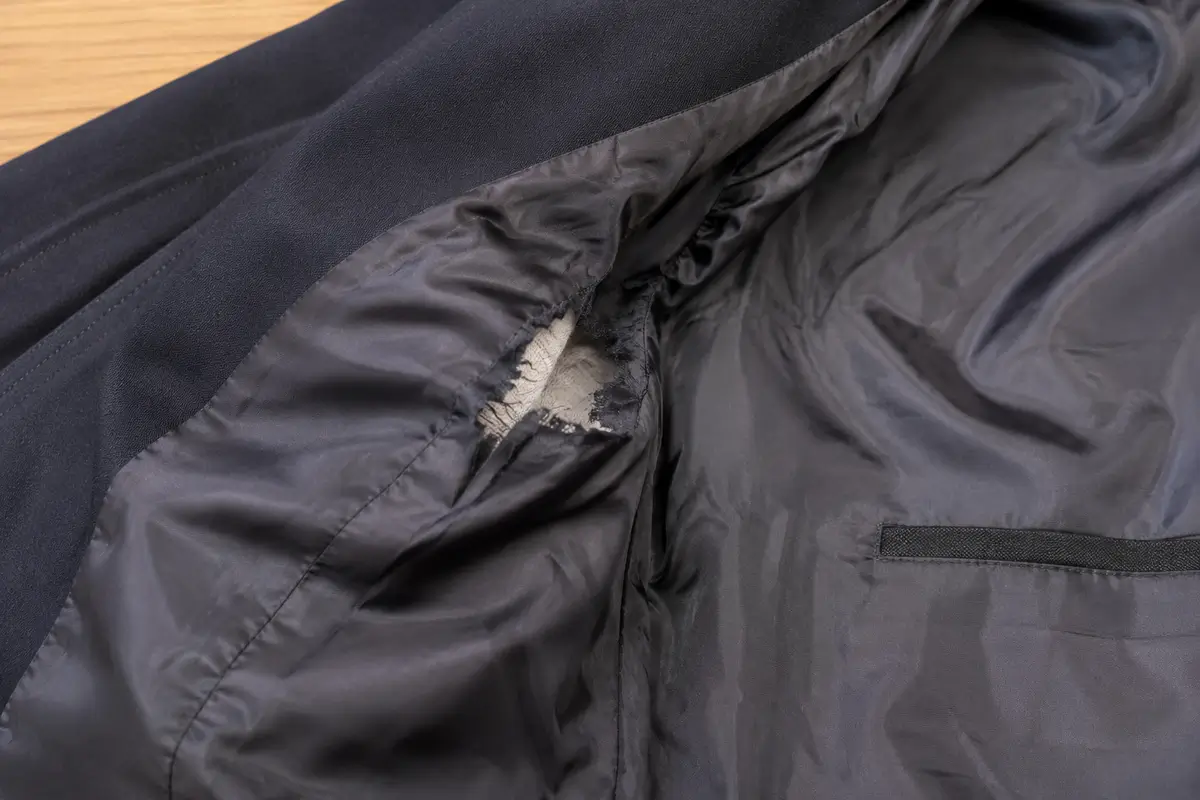 Doublure de veste déchirée sous le bras avant réparation couture invisible